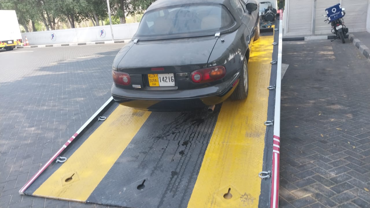 Compact sports car being recovered onto a yellow ramp